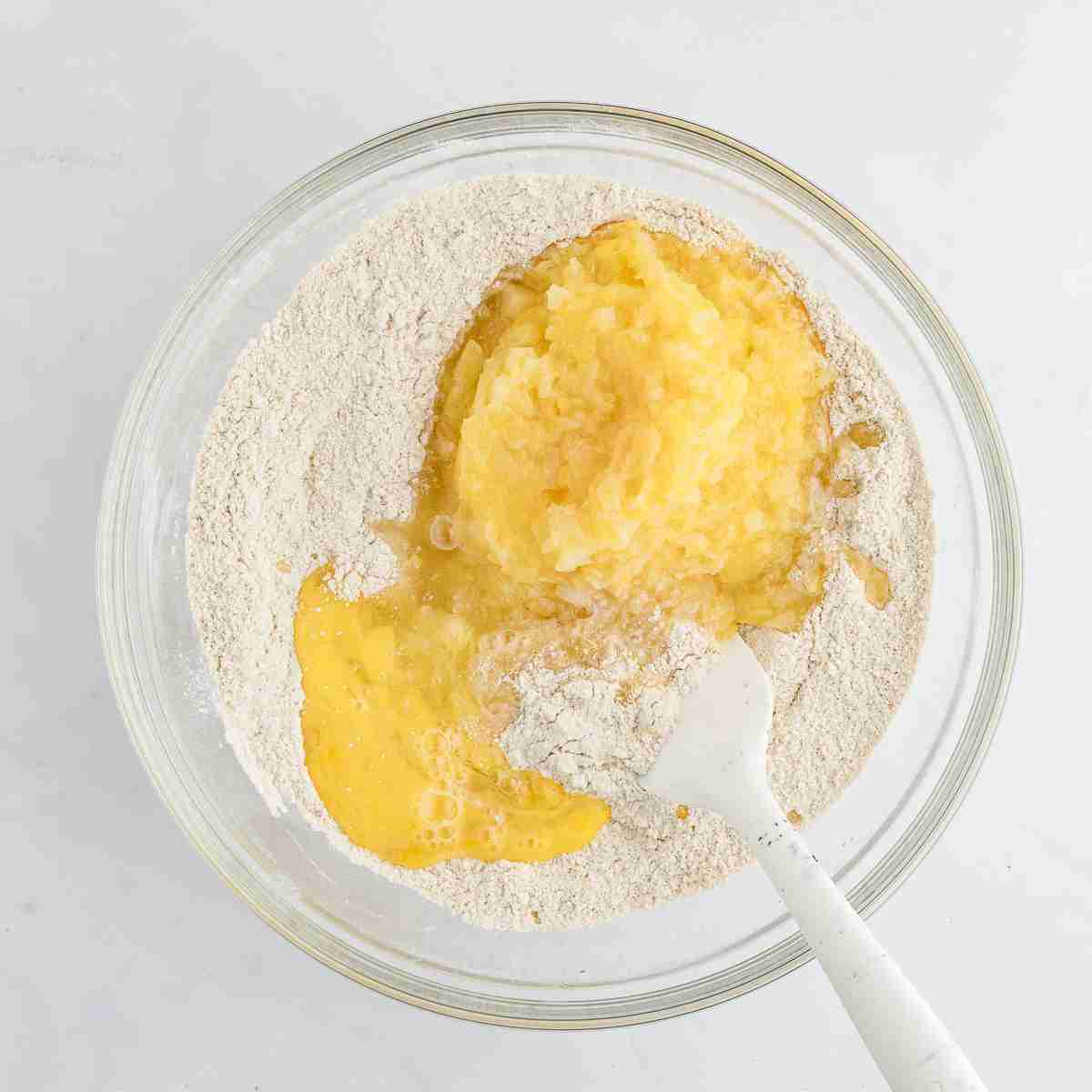 Dry cake ingredients for Granny Cake with fresh milled flour in mixing bowl with eggs and crushed pineapple added