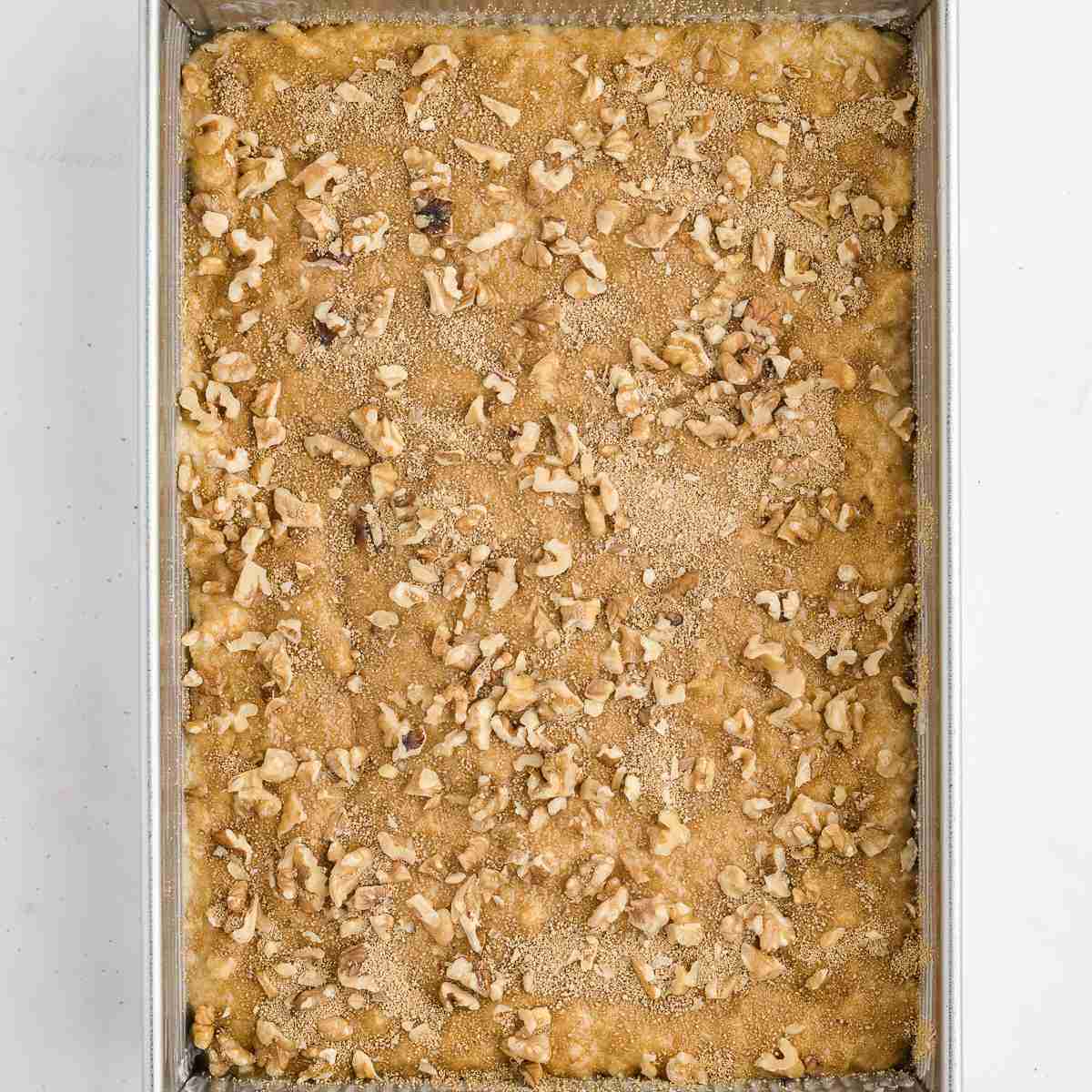 Cake pan with Granny Cake with fresh milled flour batter and first topping ingredients sprinkled on it