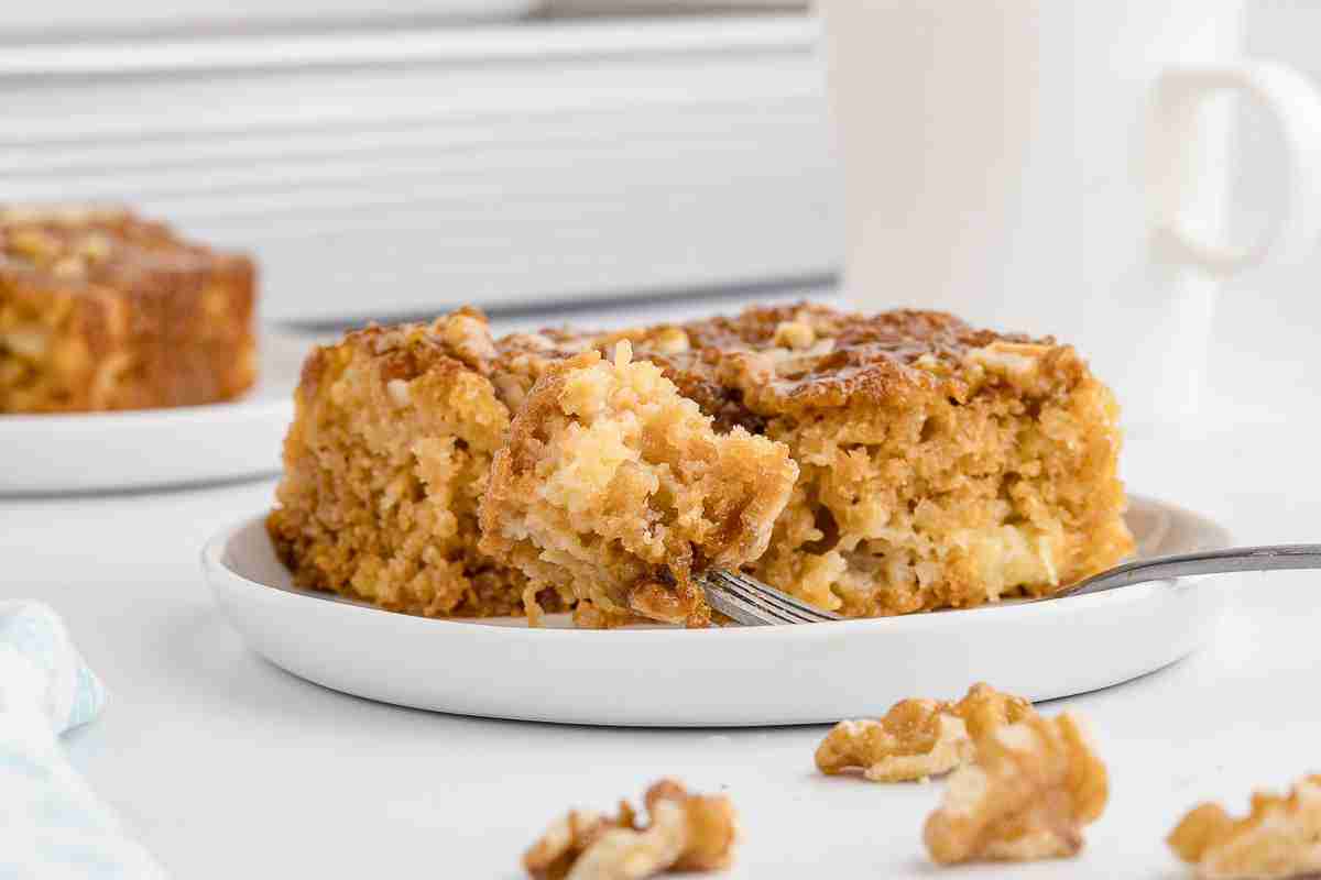A slice of Granny Cake with fresh milled flour on a white serving plate with bite on fork