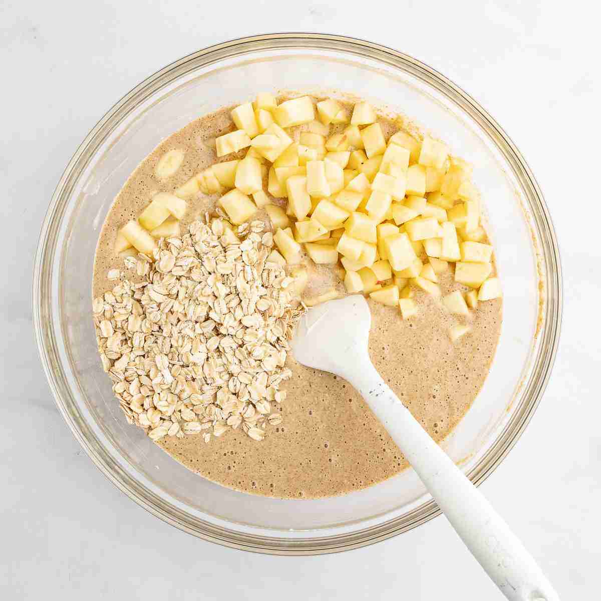 mixing bowl with apples and oats added to apple oatmeal cake batter