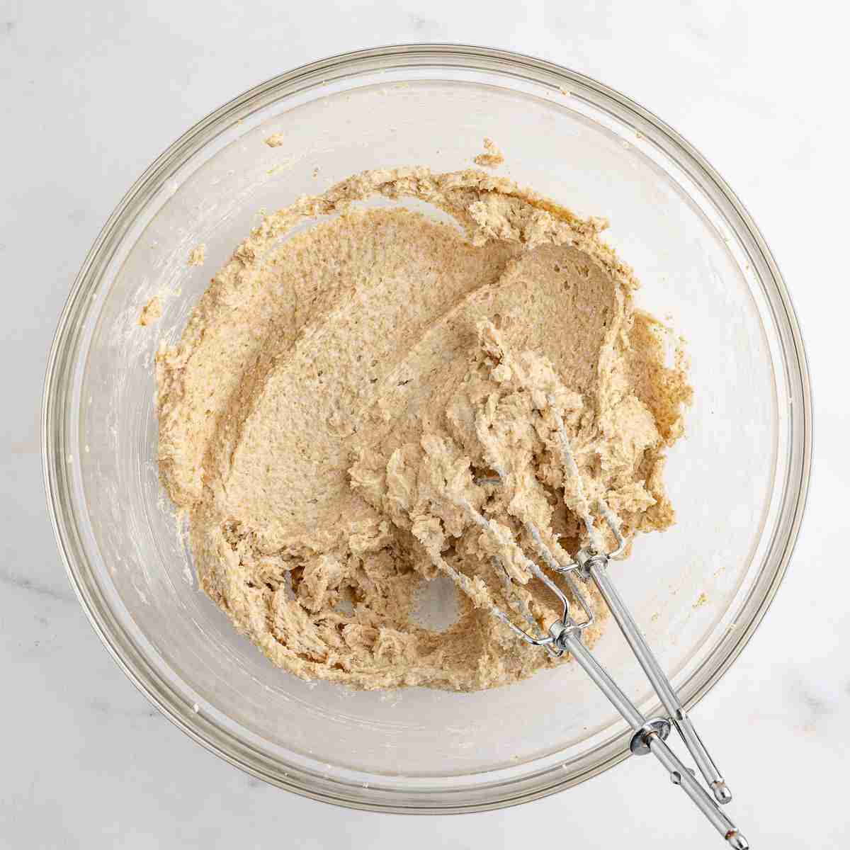 mixing bowl showing mixed butter and sugar for oatmeal raisin cookie dough