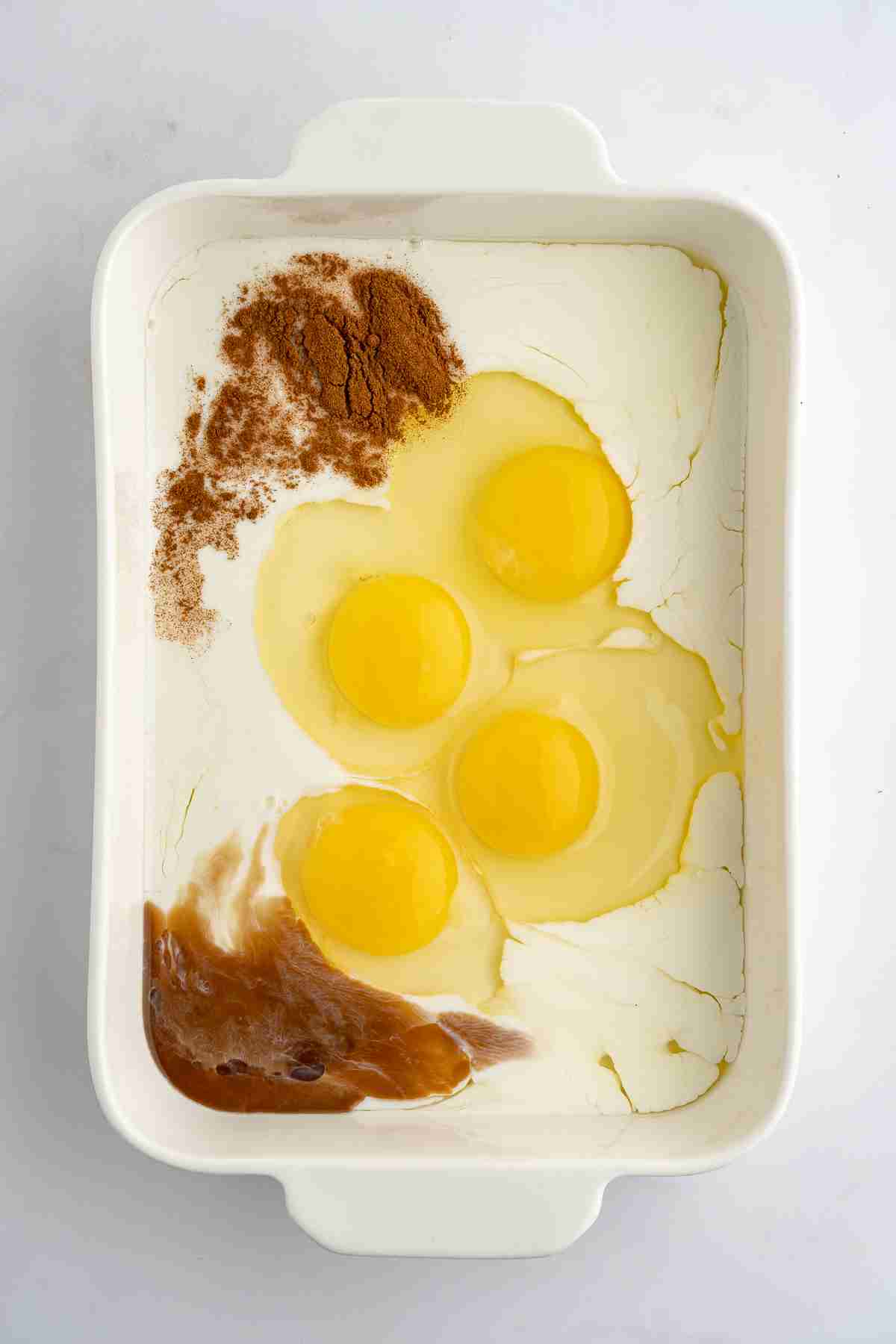 casserole dish with eggs milk cinnamon and vanilla ready to whisk