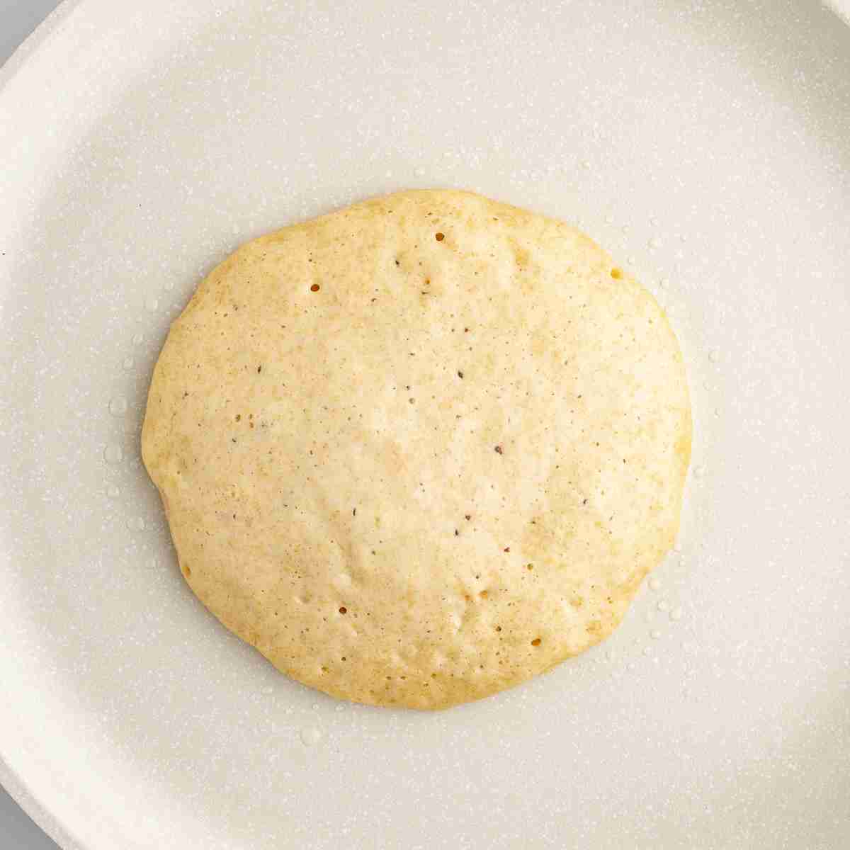 one fresh milled buttermilk pancake cooking on skillet