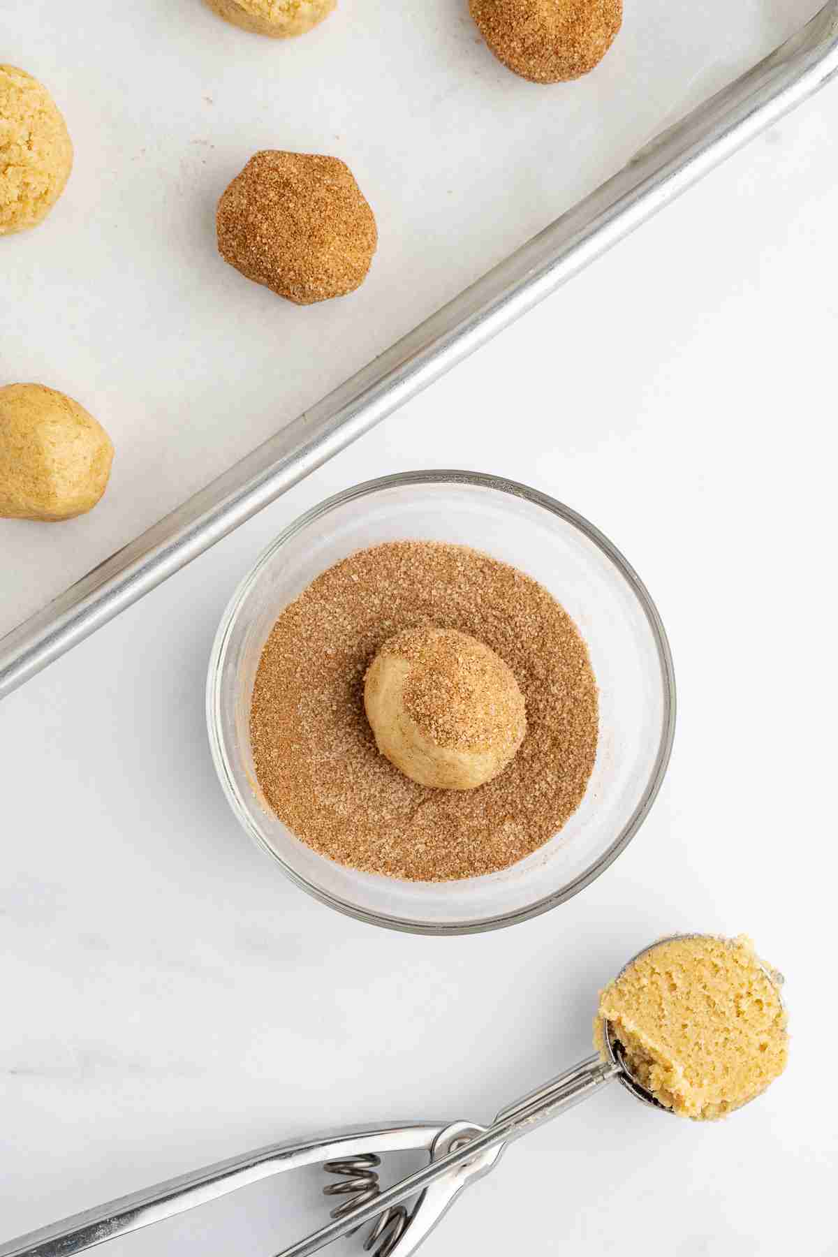 rolling fresh milled snickerdoodles dough ball in cinnamon sugar