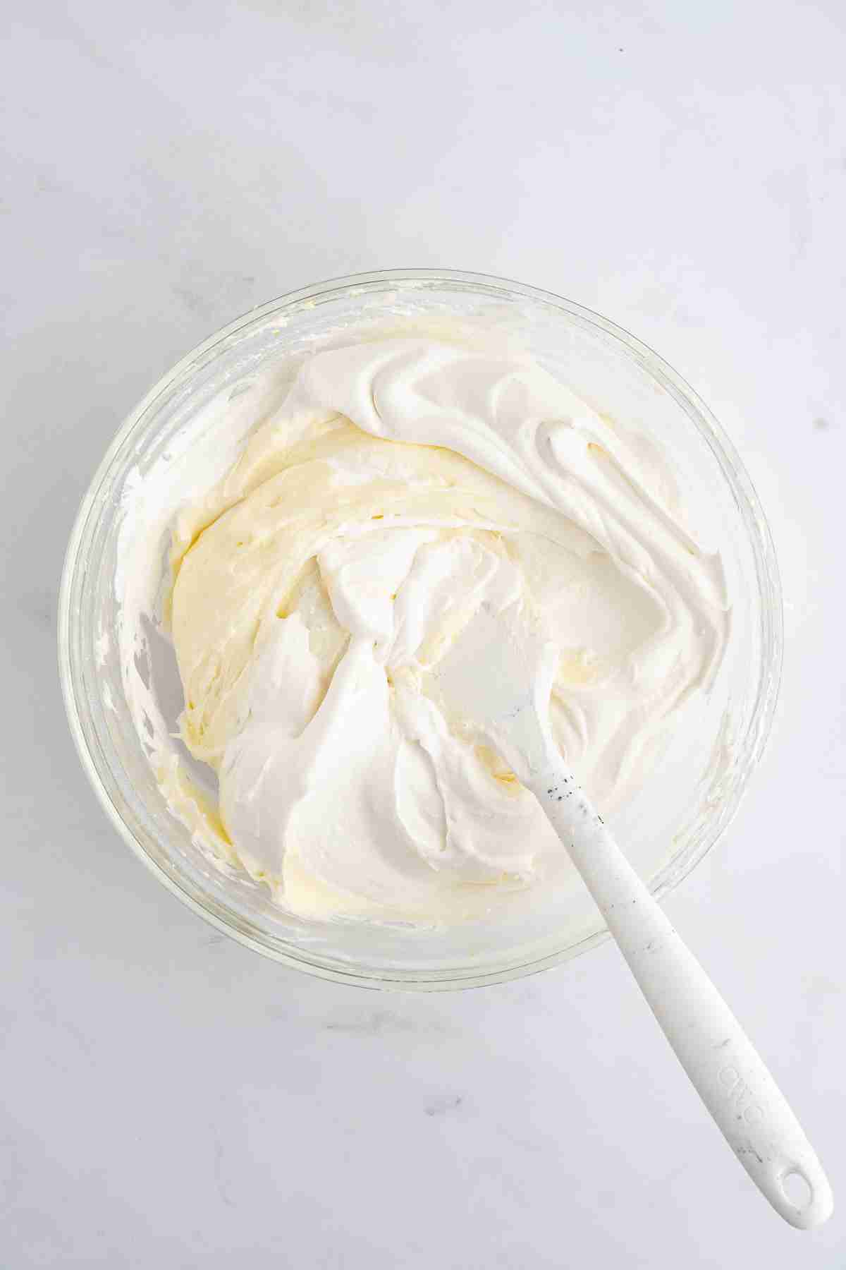 mixing bowl with lemon cheesecake filling folding in the whipped topping for lemon lush layered dessert