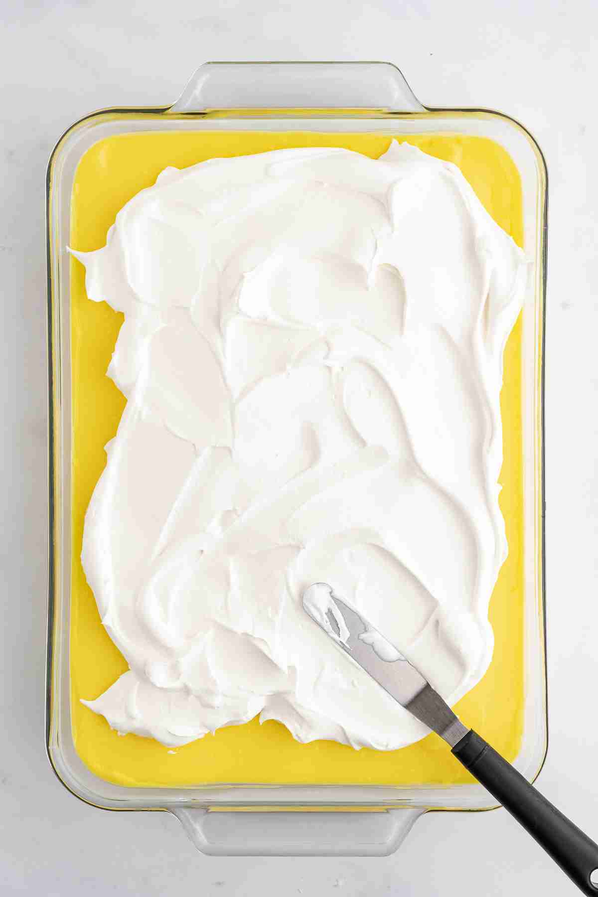 spreading whipped topping on top of pudding layer on lemon lush no bake dessert