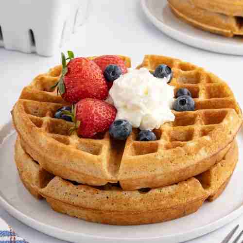 fresh milled flour waffles on white plate with whipped cream and berries