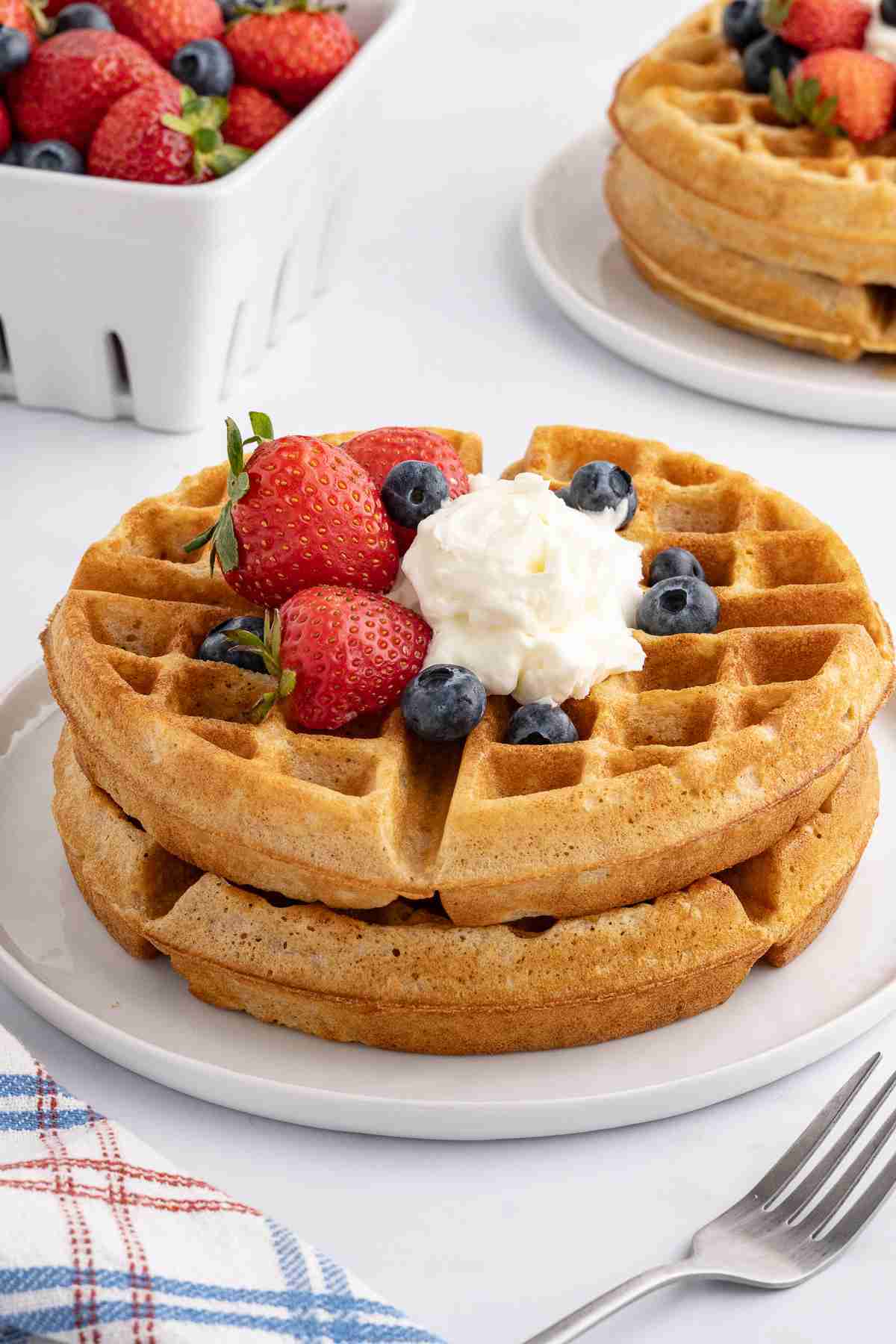 fresh milled flour waffles with whipped cream and berries on white plate