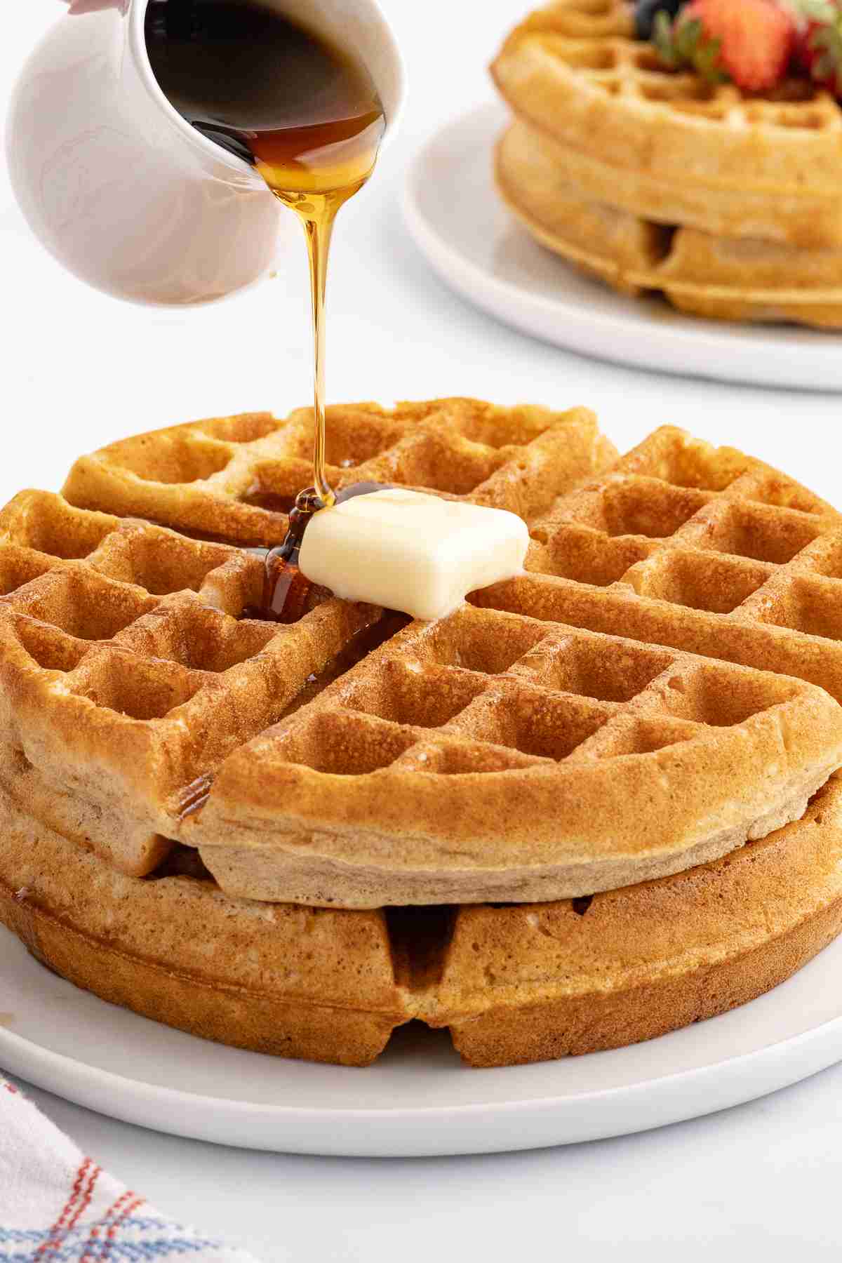 fresh milled waffles with butter and syrup being poured