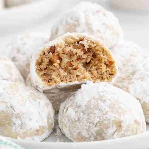 a plate of fresh milled mexican wedding cookies with one cookie showing inside texture