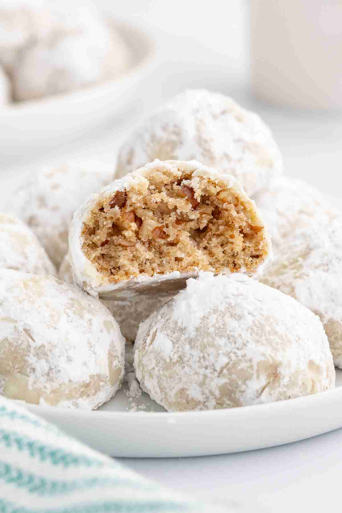 a plate of fresh milled mexican wedding cookies with one cookie showing inside texture
