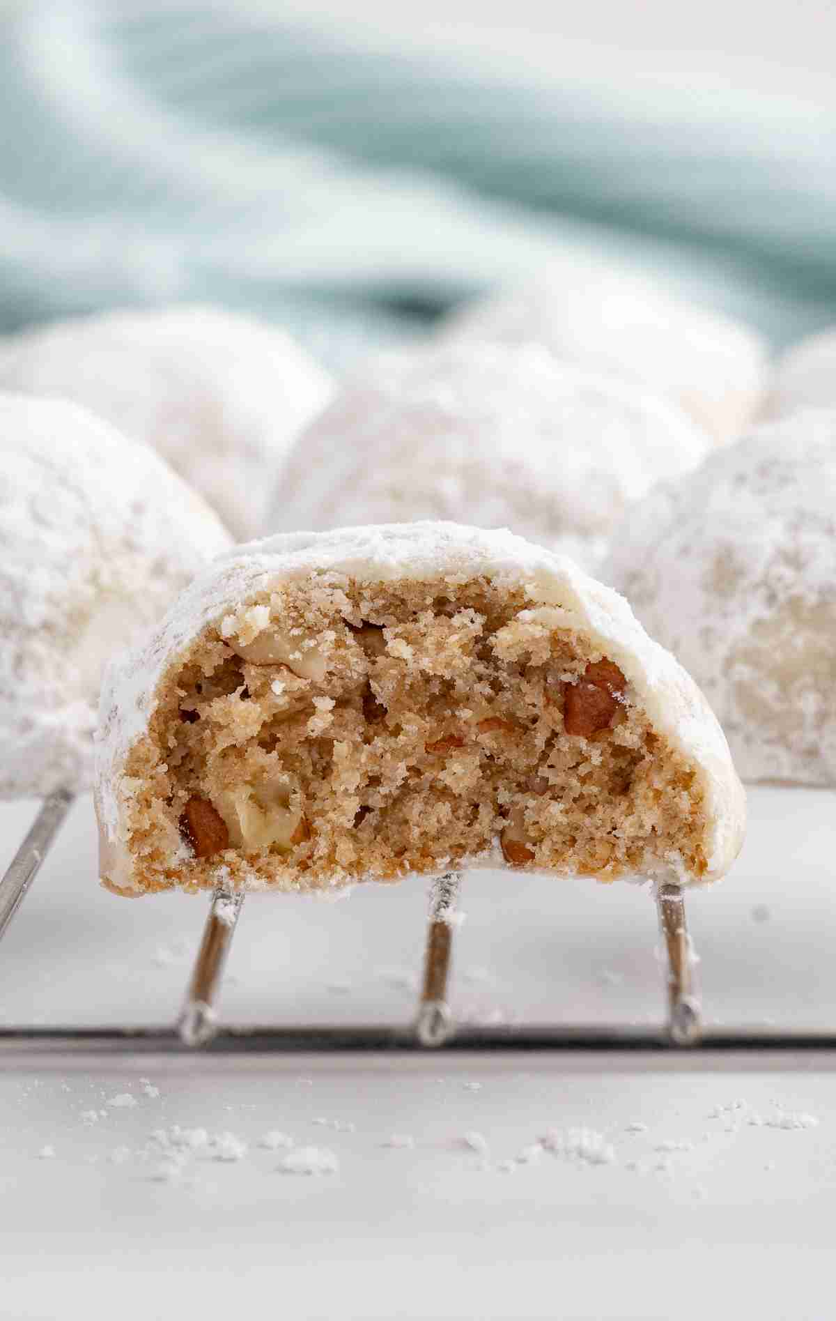 close up of one fresh milled mexican wedding cookie showing inside texture with more cookies in the background