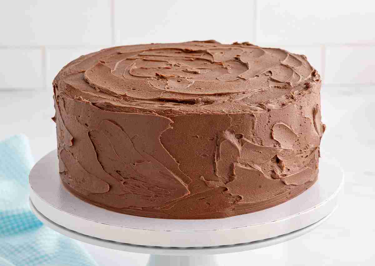 uncut fresh milled chocolate cake on white cake stand