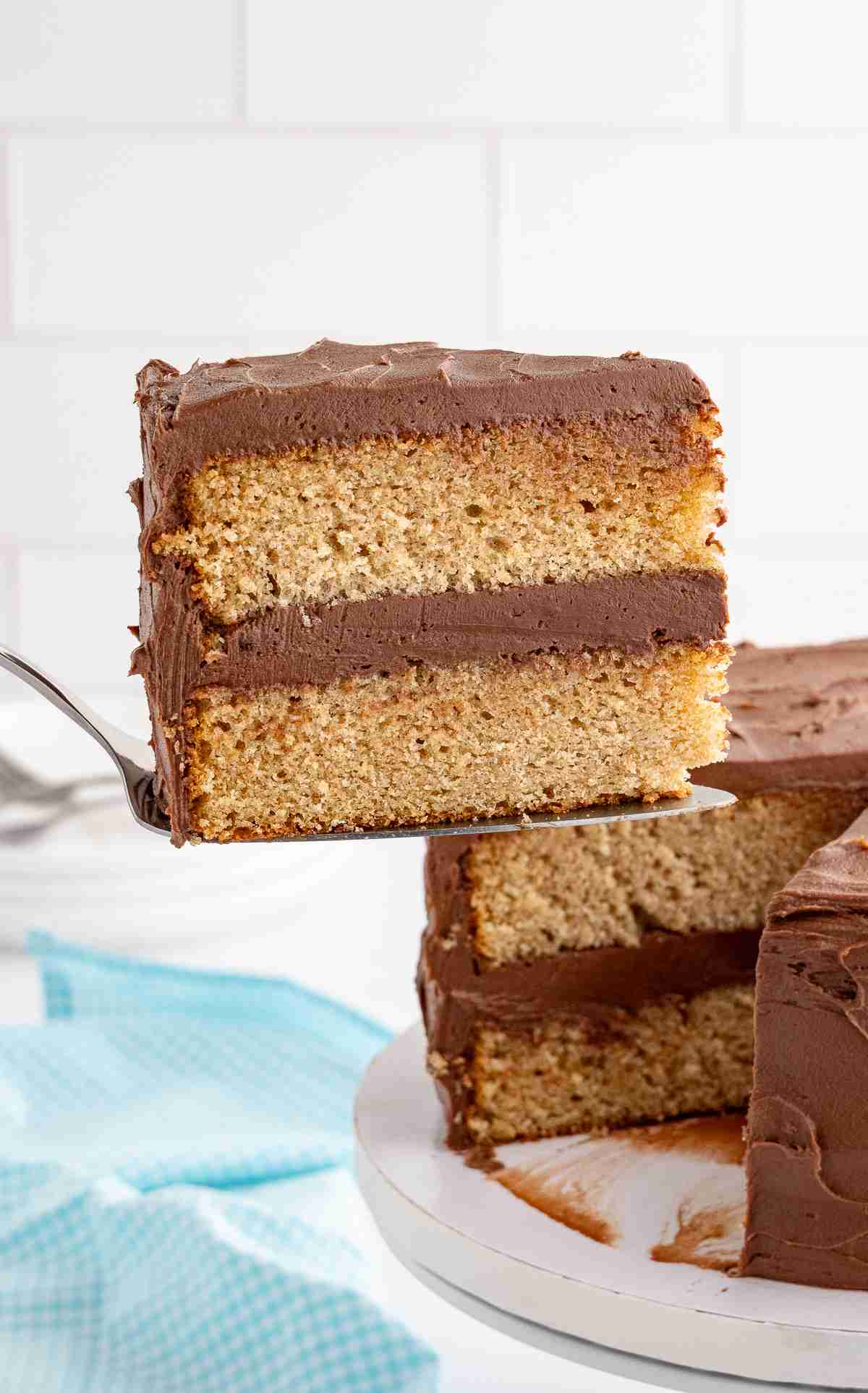 a slice of fresh milled yellow cake with chocolate frosting on serving spoon with cake in background