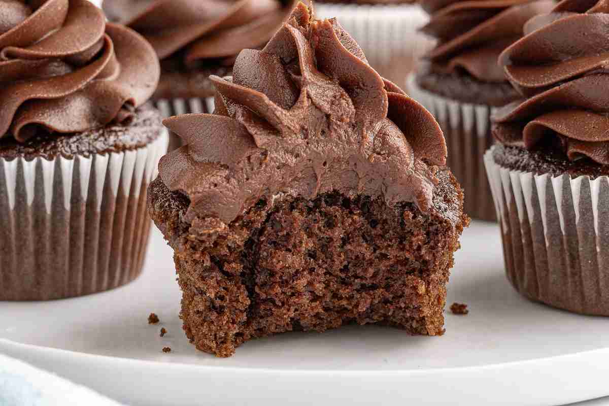 a fresh milled chocolate cupcake with bite taken out showing inside texture and more cupcakes in background